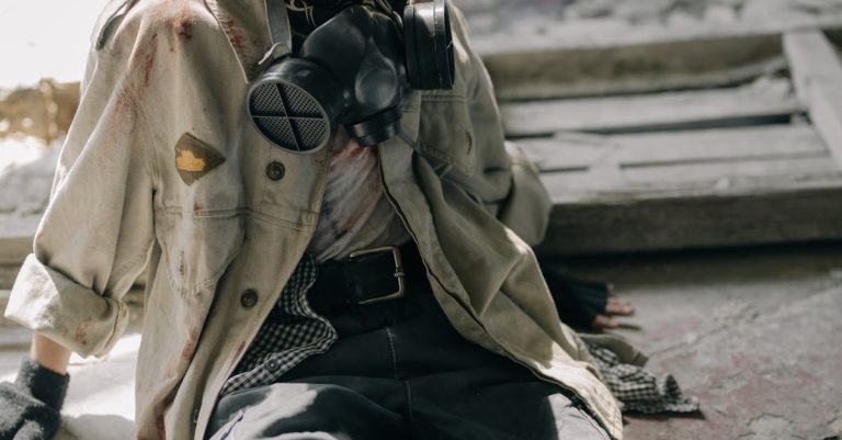 A young man sitting inside an abandoned building wearing a gas mask.